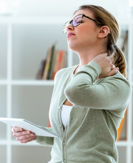 Woman holding her neck, visibly struggling with pain